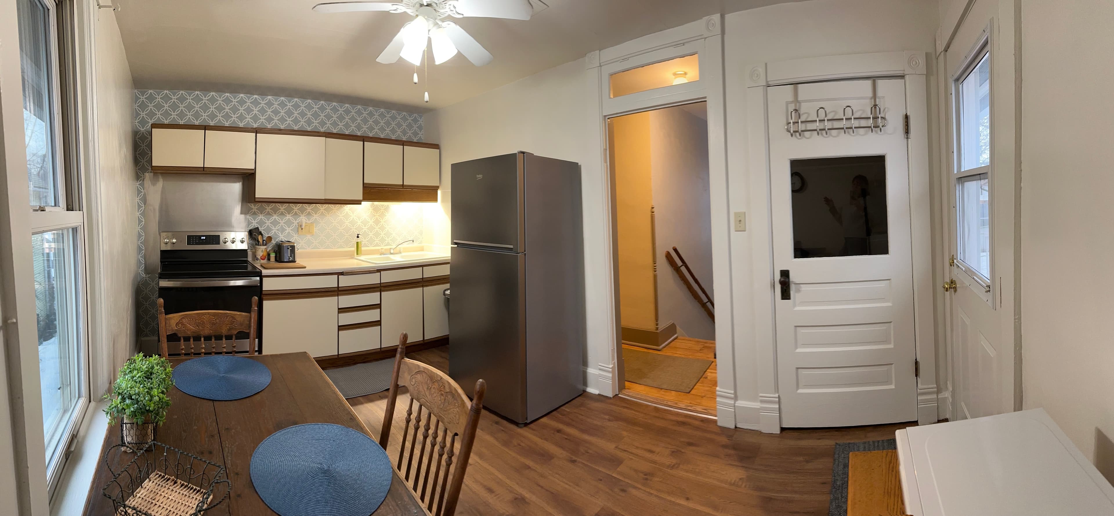 A cozy kitchen featuring wooden furniture, modern appliances, and an entrance to a hallway.