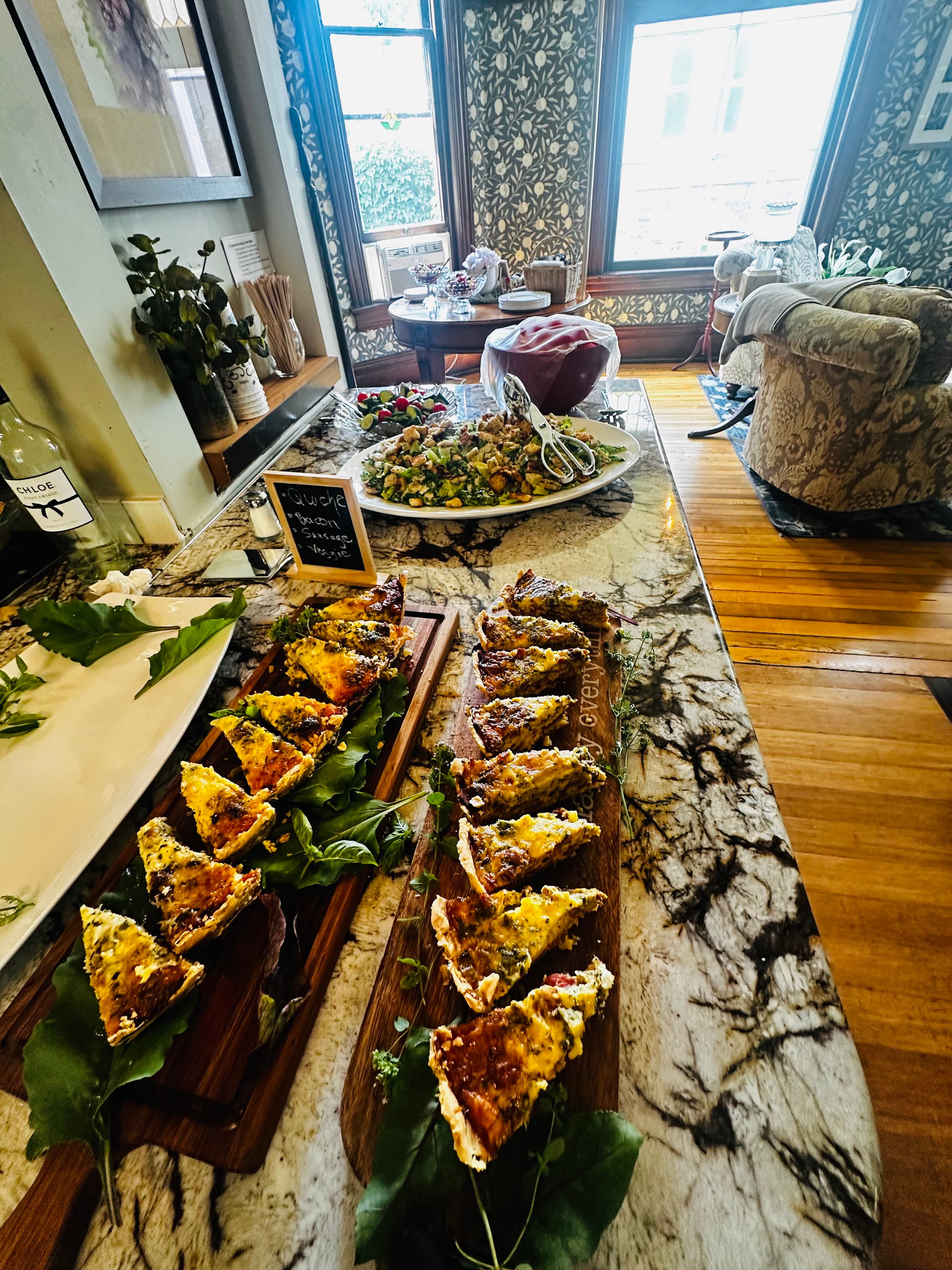 A cozy dining area featuring slices of quiche on wooden boards beside a colorful salad and decorative table settings.