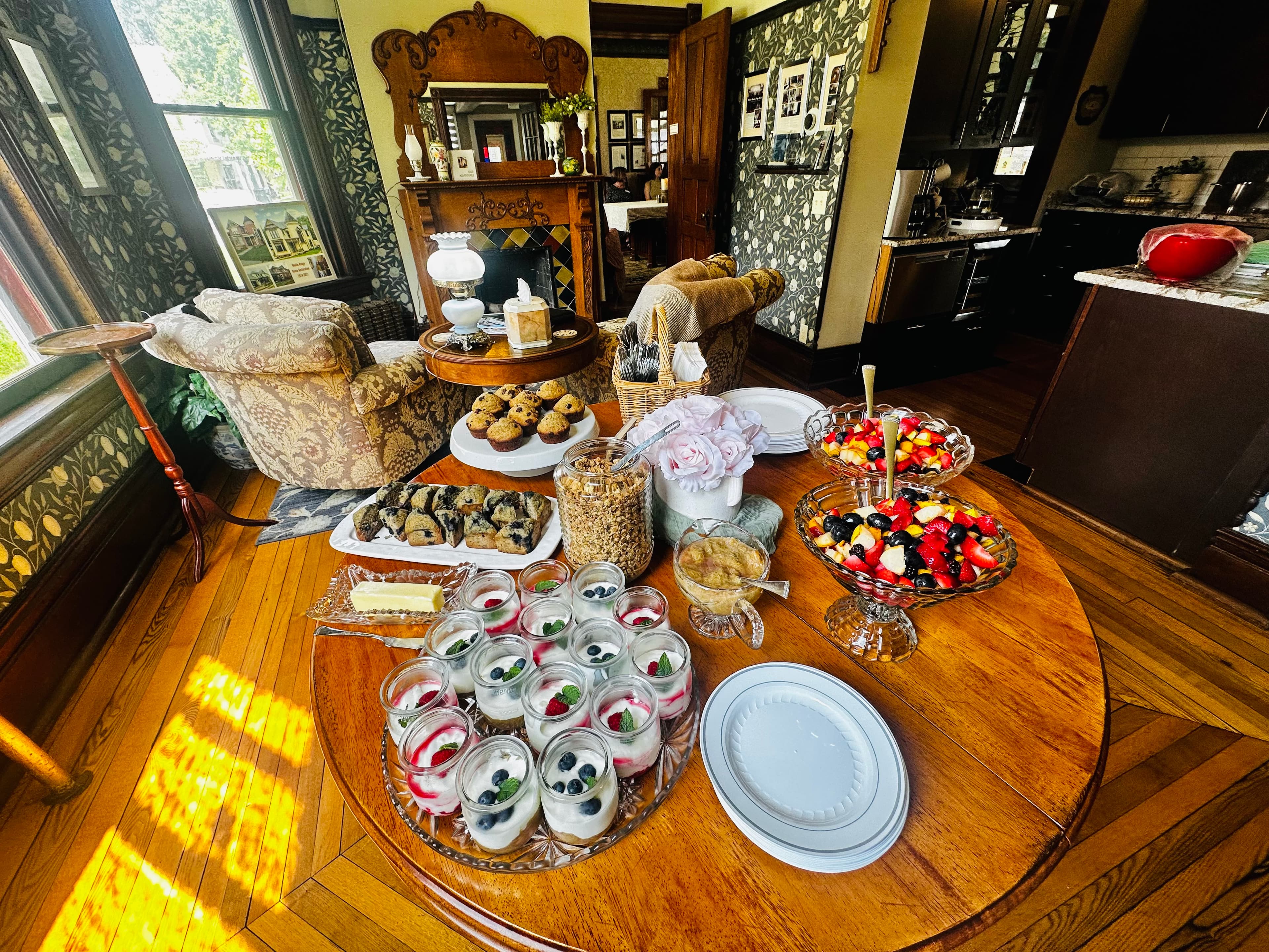 A beautifully set table with an array of desserts and snacks in a cozy, vintage room.