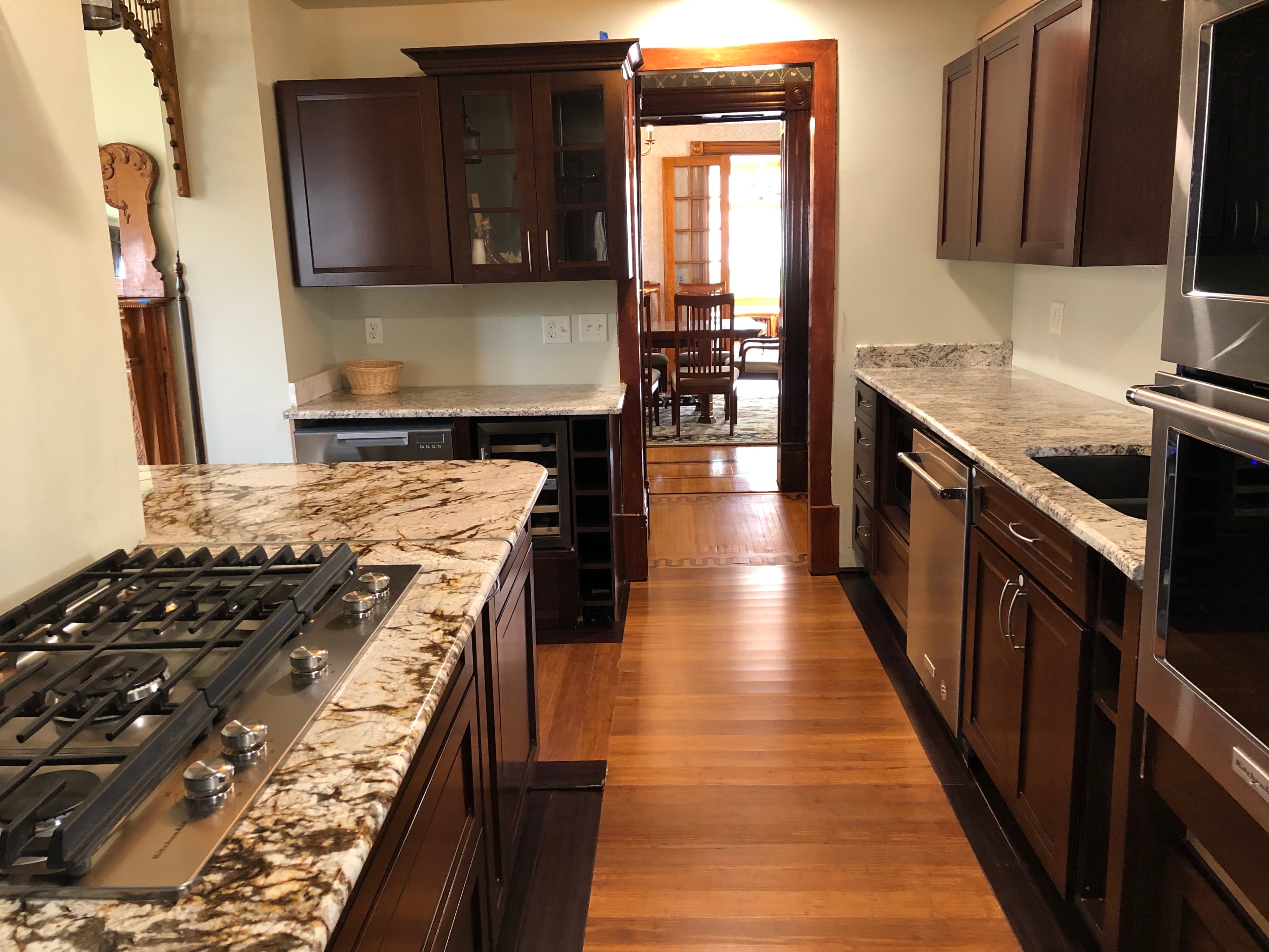 Modern kitchen with dark wood cabinets, granite countertops, and a view into a dining area.