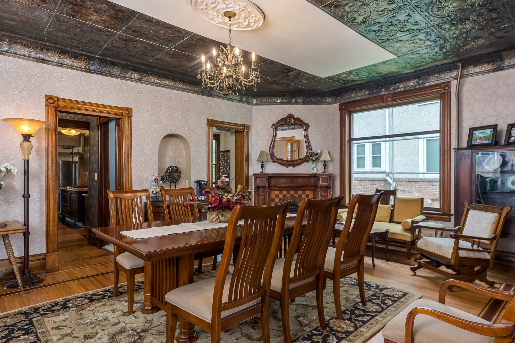 A vintage dining room featuring a wooden table, elegant chairs, and ornate ceiling details.